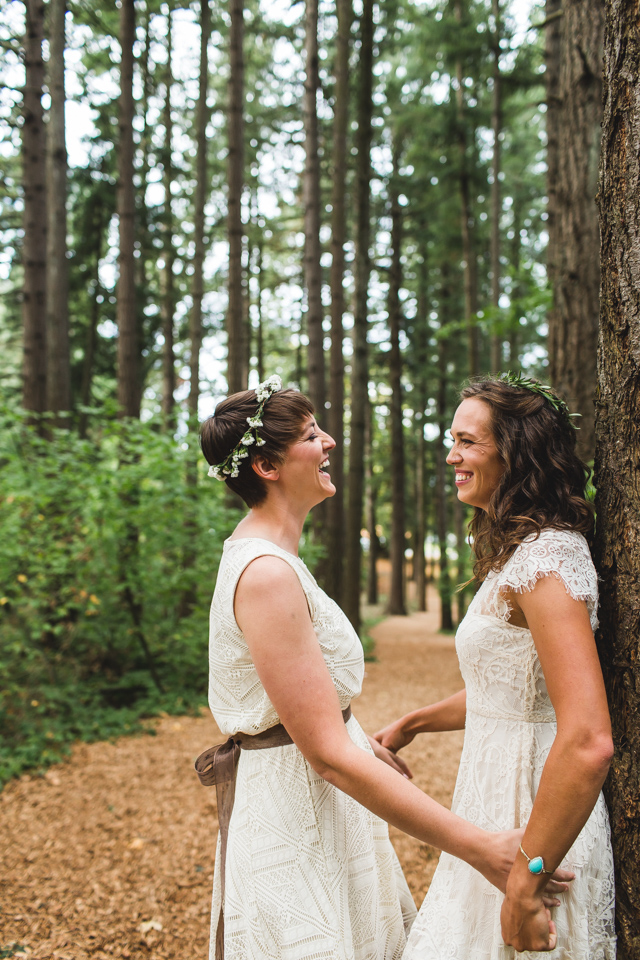 bride and bride laughing in woods at portland oregon same sex wedding
