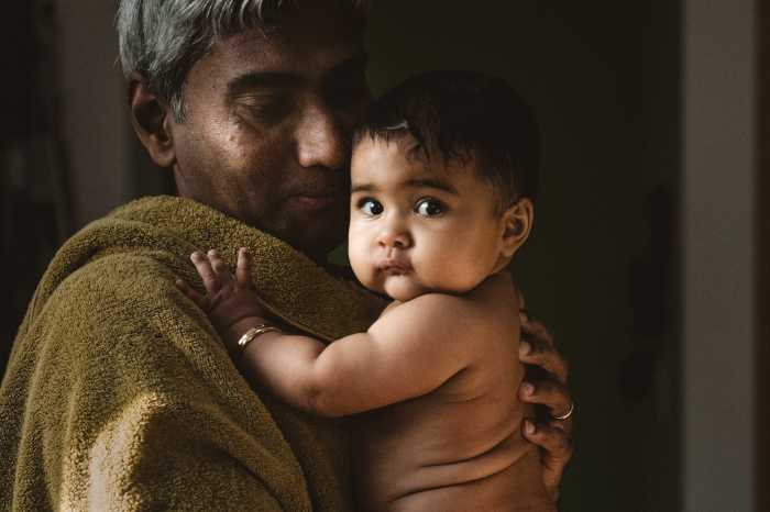 beautiful portrait of baby with no shirt on being cuddled by grandparent