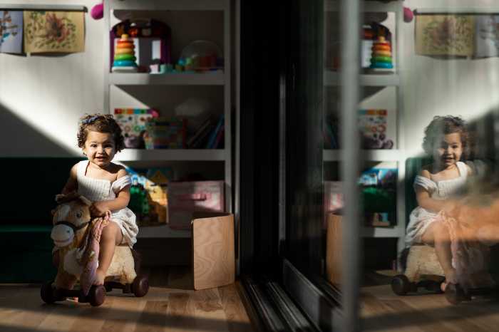 Girl toddler riding toy inside next to mirror family photographer